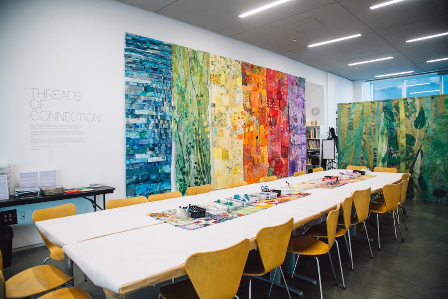 Large colorful wall panels and a long table with a white covering and art materials in the Bank of America Art Lab