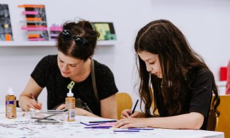 A woman and girl concentrating and looking down while making art during an ICA Play Date.