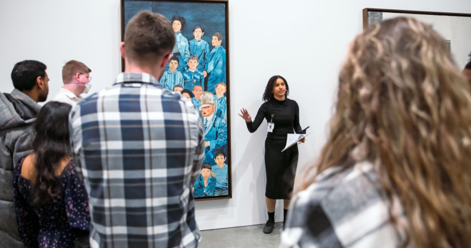 People gather around an ICA employee speaking about a painting