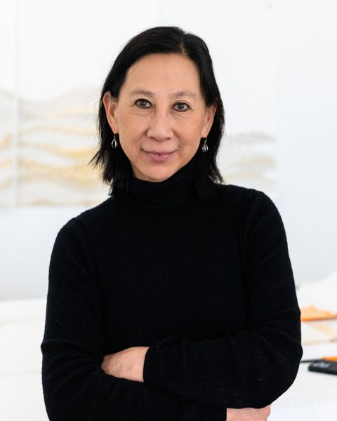 Person with black shoulder length hair in black sweater in a studio space