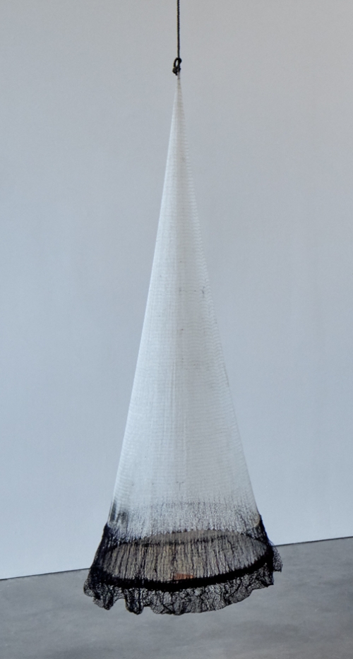 a Cónica hanging sculpture made from a fishing net that is white except for a dark bottom, the largest part.