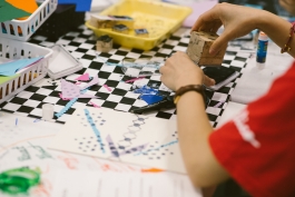 An art-making table full of art supplies, and a youth creating a stamp