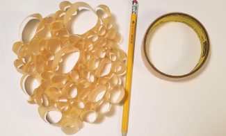 Loops of tape sticked together to form an amorphous shape, next to a number two pencil and a role of tape.