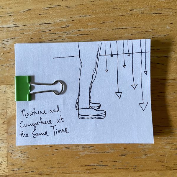 A drawing of legs standing before a series of hanging pendulums on a white index card with a green binder clip.