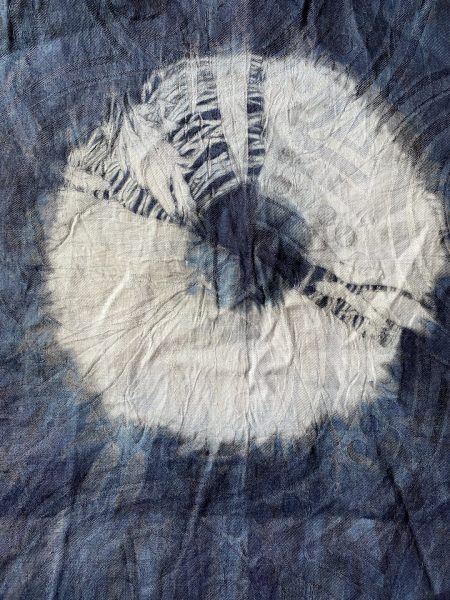 Faded blue fabric with white circular dyed design in the center