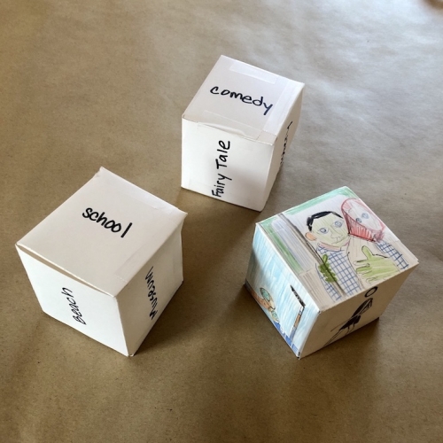 Three dice: one with drawings of characters, and two with writing, on each side.