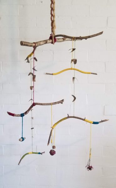 Hanging mobile made of sticks wrapped with yarn and other natural materials