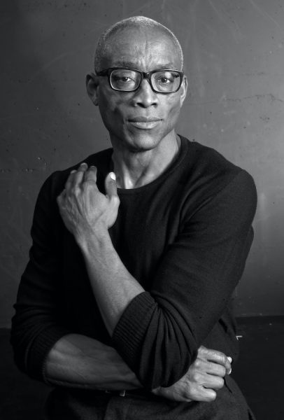 Black-and-white eadshot of Bill T. Jones, an older, medium-dark-skinned man with dark-rimmed glasses, a dark shirt, and a serious expression.