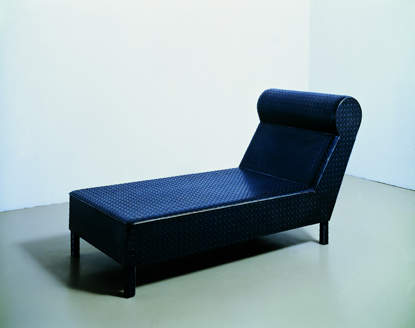 A sculpture made of a black steel tread plate shaped to form a long chaise.