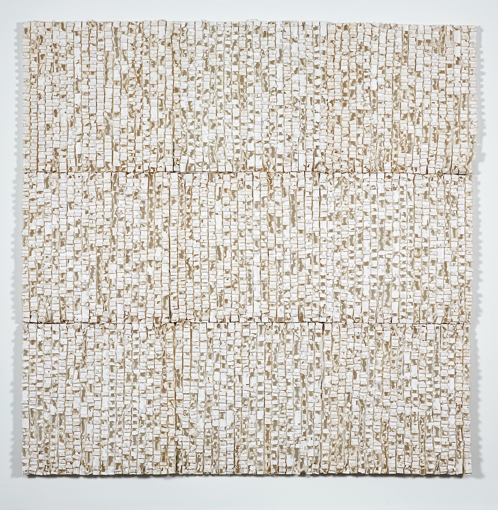 A relief sculpture in a grid pattern formed by layers of cast whiteish paper.