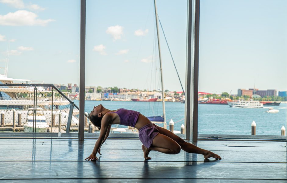A dancer in purple in the ICA theater with views of Boston Harbor
