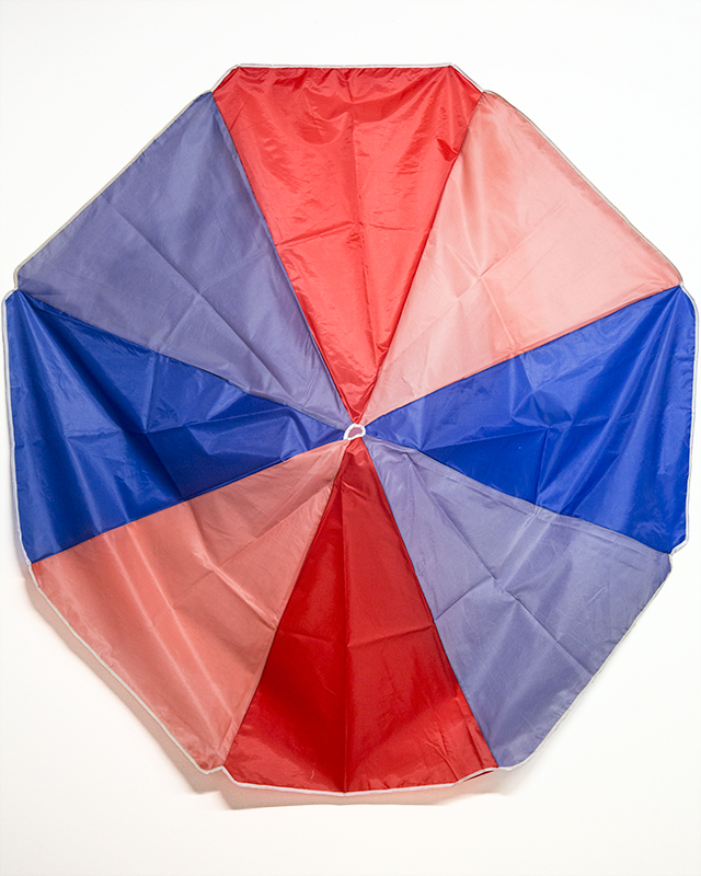 A sculpture composed of red and blue fabric panels removed from an umbrella, some bright and some faded.