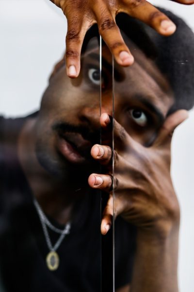 A portrait of an African-American man with his finger tips between a glass crevice.