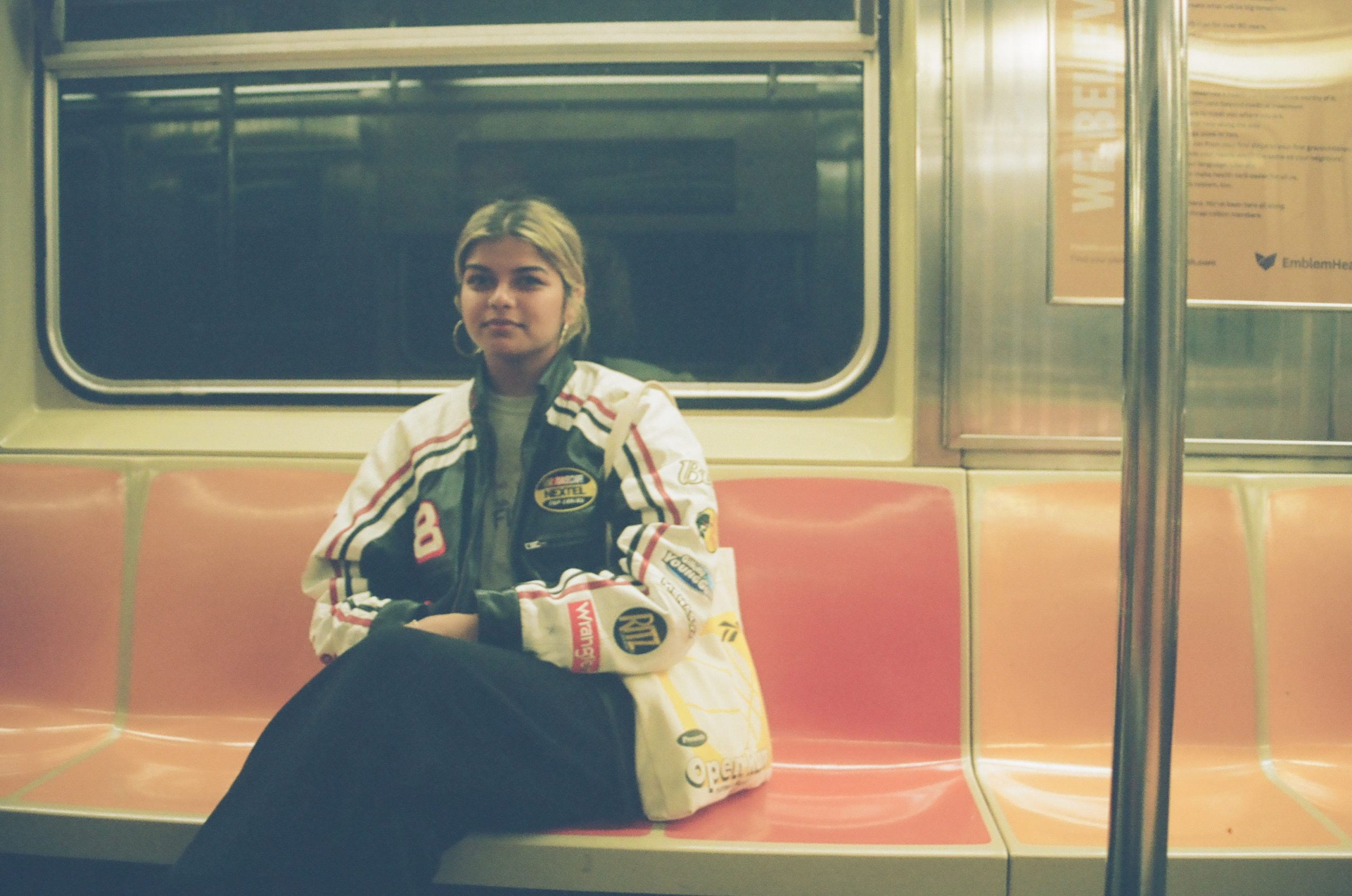 A medium dark skinned person with blonde hair riding on a subway train.