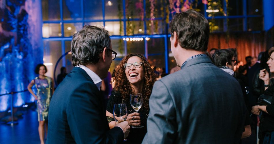 A group of people laughing and holding wine glasses in the ICA lobby