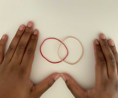 Two rubber bands lying on top of each other, intersecting at the middle.