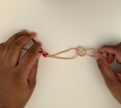 Pulling a rubber band through a loop to create a third chain