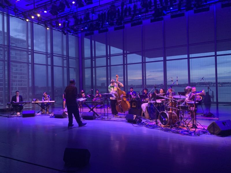 Orchestra band playing on the ICA Stage lit in blue light