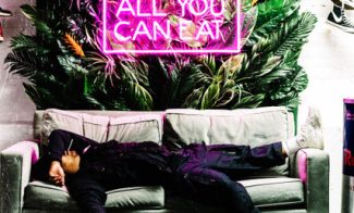 A person laying on a couch under a neon sign reading ALL YOU CAN EAT.