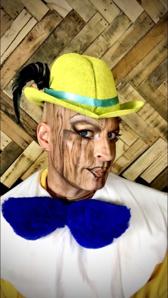 Kurt Fowl wearing a yellow hat, drag makeup, and a blue bow tie.