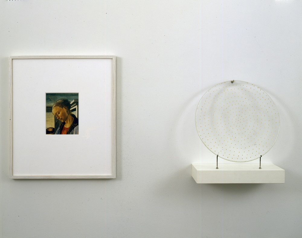 An installation of two objects hung side by side a framed reproduction of Sandro Botticelli's 