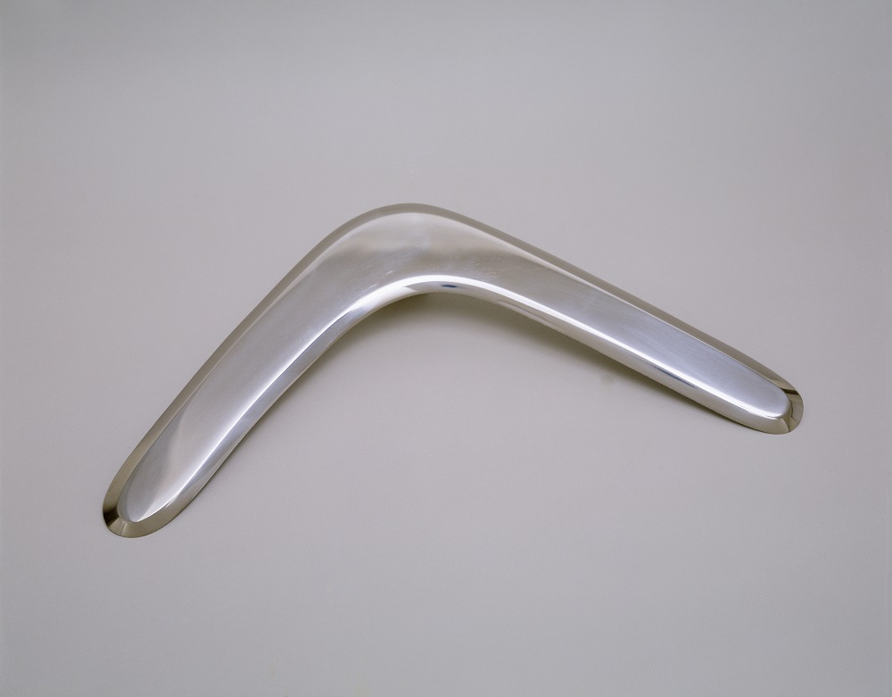 A sleek, polished, stainless-steel boomerang on a light background. 