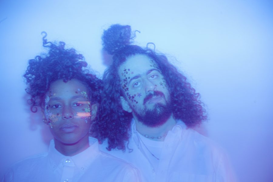 The two members of Optic Bloom with stars on their faces in a blue colored photograph. 