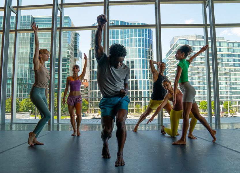 A group of dancers performing in front of large windows