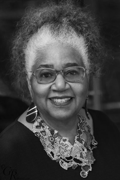 Black and white headshot of a Black woman with glasses and an ornate necklace