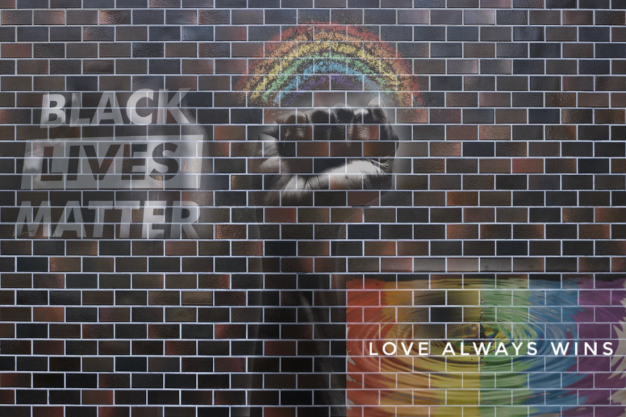 A brick wall with a raised fist in the center, rainbow flag with the words 