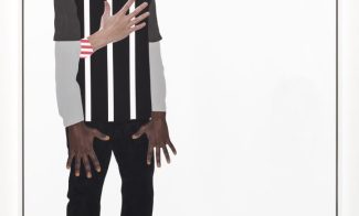 A mixed media collage depicts a Black boy in a striped shirt, dark pants, and sneakers standing to the left of a vertical white canvas. His hands hang in front of him with outstretched fingers and a light-skinned hand rests on his chest.