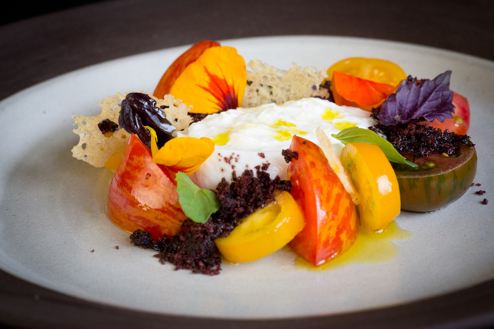 A tomato and ricotta dish with herbs and flower decoration