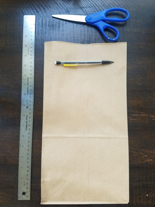 Measuring a rectangular piece of paper with a pencil and scissors nearby