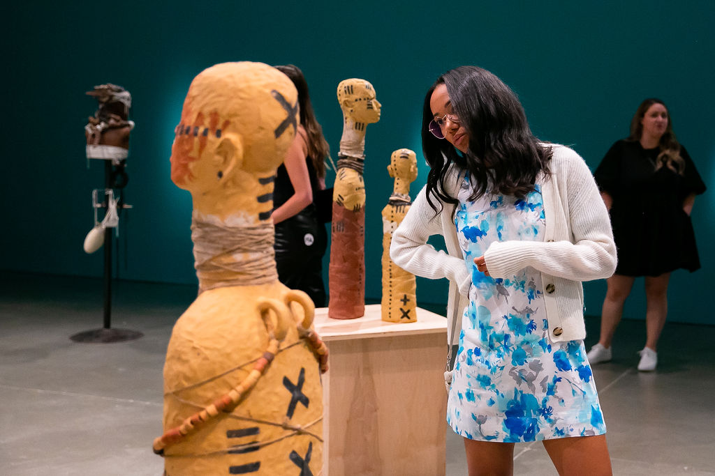 Visitors looking at clay figures with black linear markings