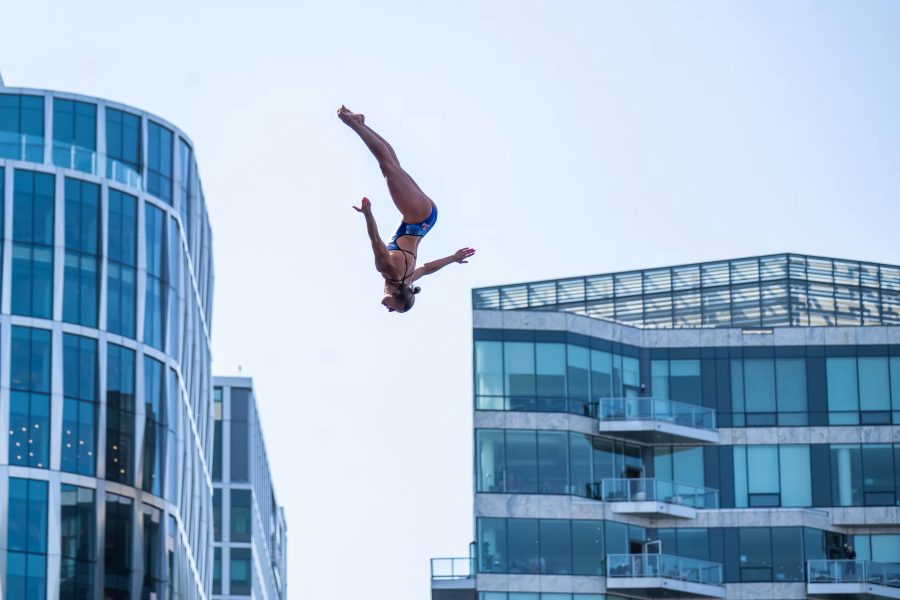 Person diving through air among Seaport skyline