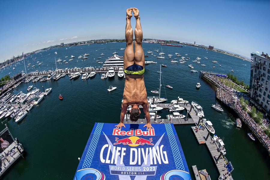Diver doing handstand from diving board above Boston Harbor