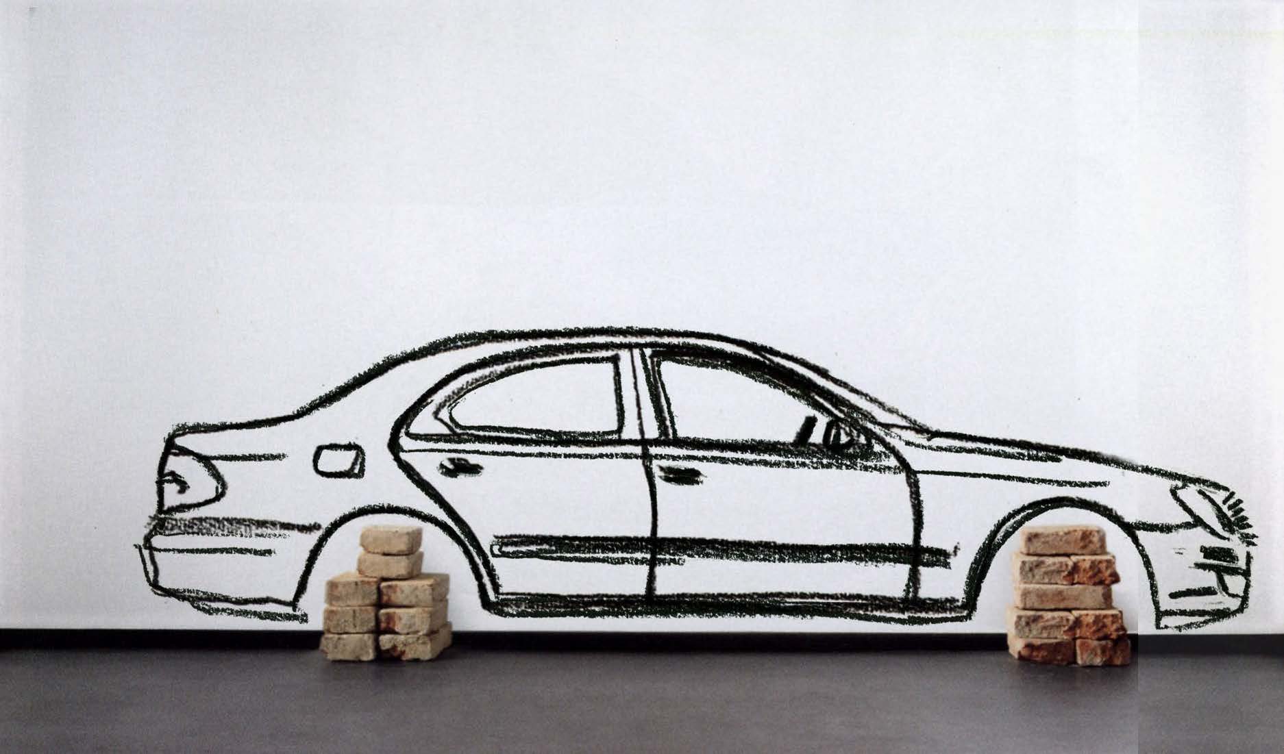 Large drawing of a car on a wall with two piles of bricks stacked where tires would be