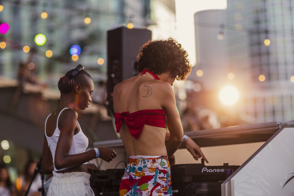 Two DJs at a booth outdoors in Seaport around sunset