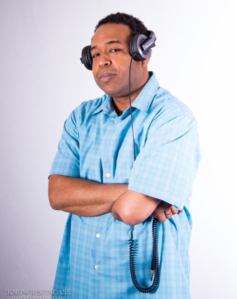 a man wears headphones and poses with his arms crossed