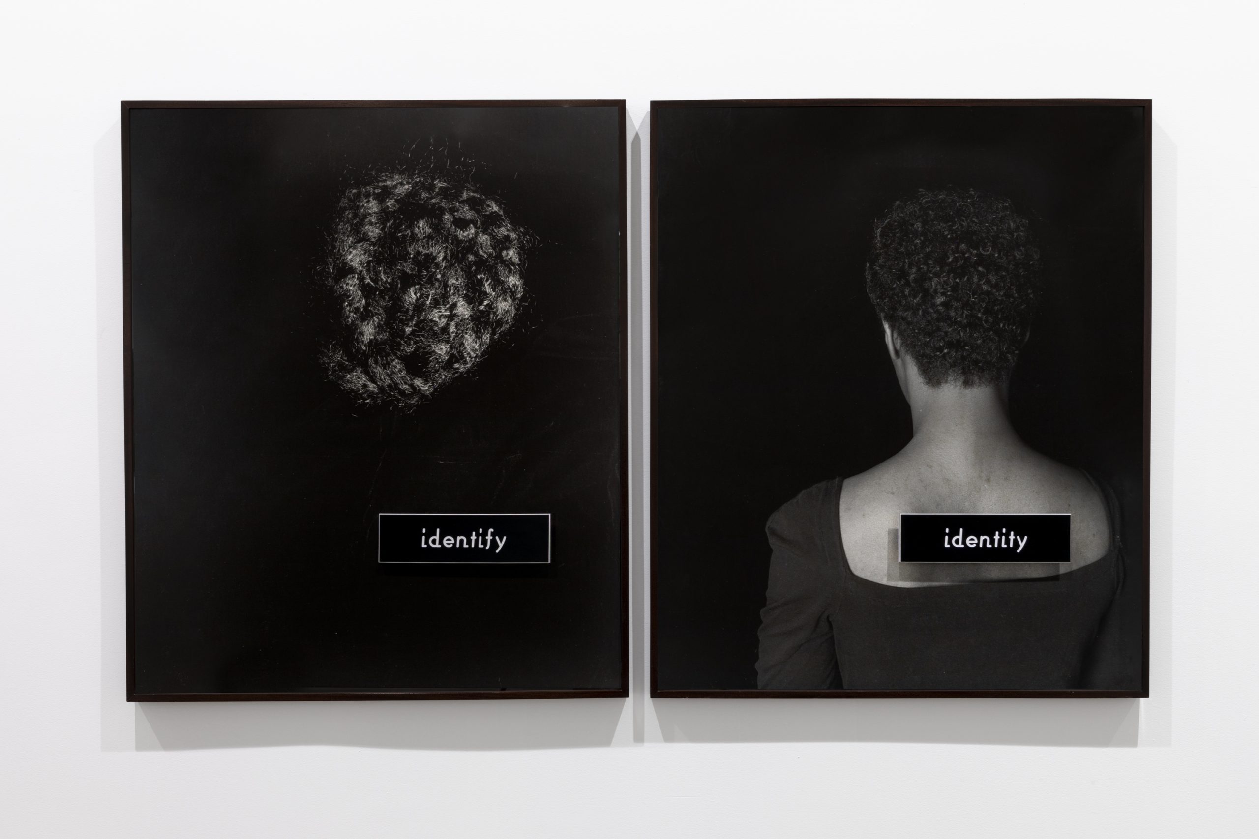 Two black-and-white photographs with black backgrounds, one of a section of dark, curly hair with a placard reading “identify” and one a portrait of a Black woman in a scoop-neck black top shown from the back with a placard reading “identity” affixed to the bare skin of her upper back.