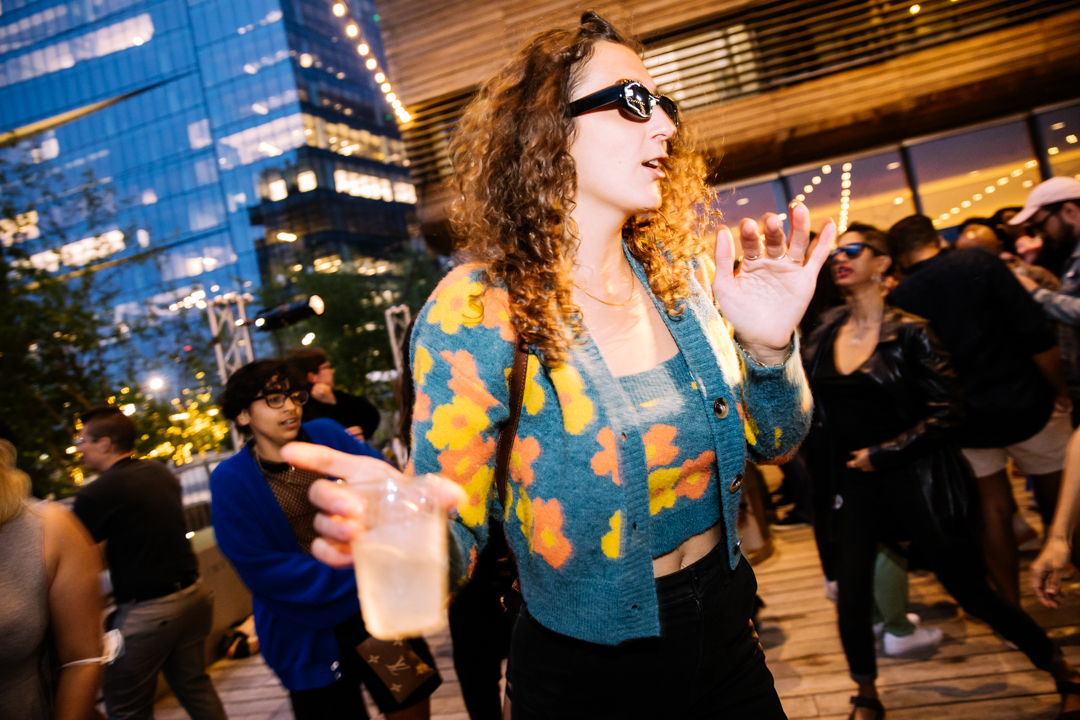Person dancing with sunglasses and drink in their hand 