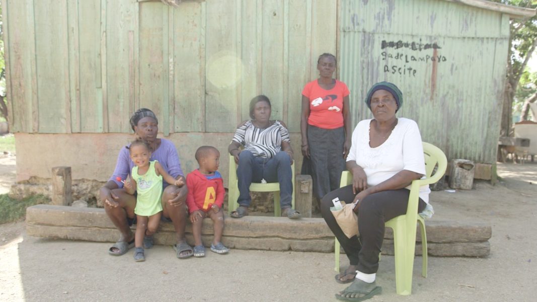 A group photo of a Black family outdoors next to a rundown building