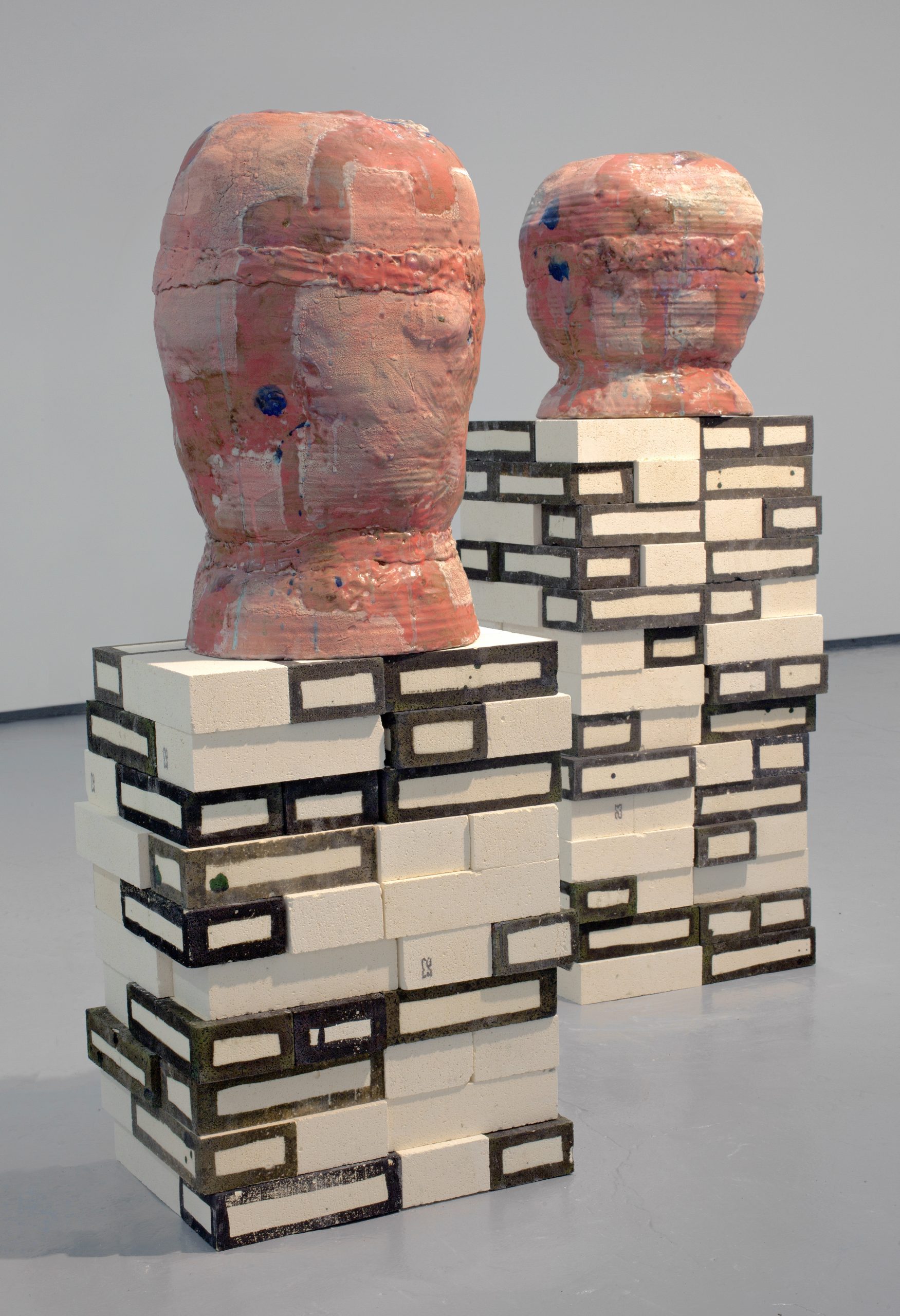 Photography of sculpture, two ceramic forms resting on top of two pillars made from kiln bricks