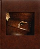 Photo of a brown hardcover book with a photo of a tear in a leather armchair embossed into the front