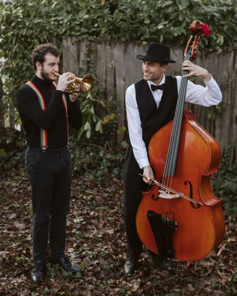 Portrait of two men in old fashioned clothes with a string bass and trumpet outdoors