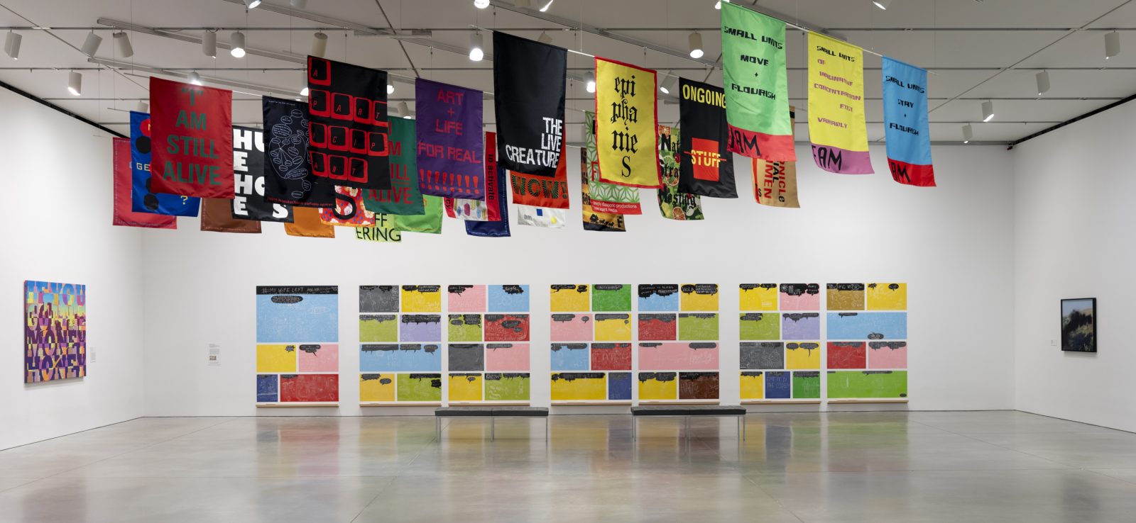 Gallery with many colorful printed flags hanging on the ceiling and a long wall with colorful tiles