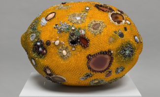 Sculpture of a lemon with molding patterns on it made of gems and rocks