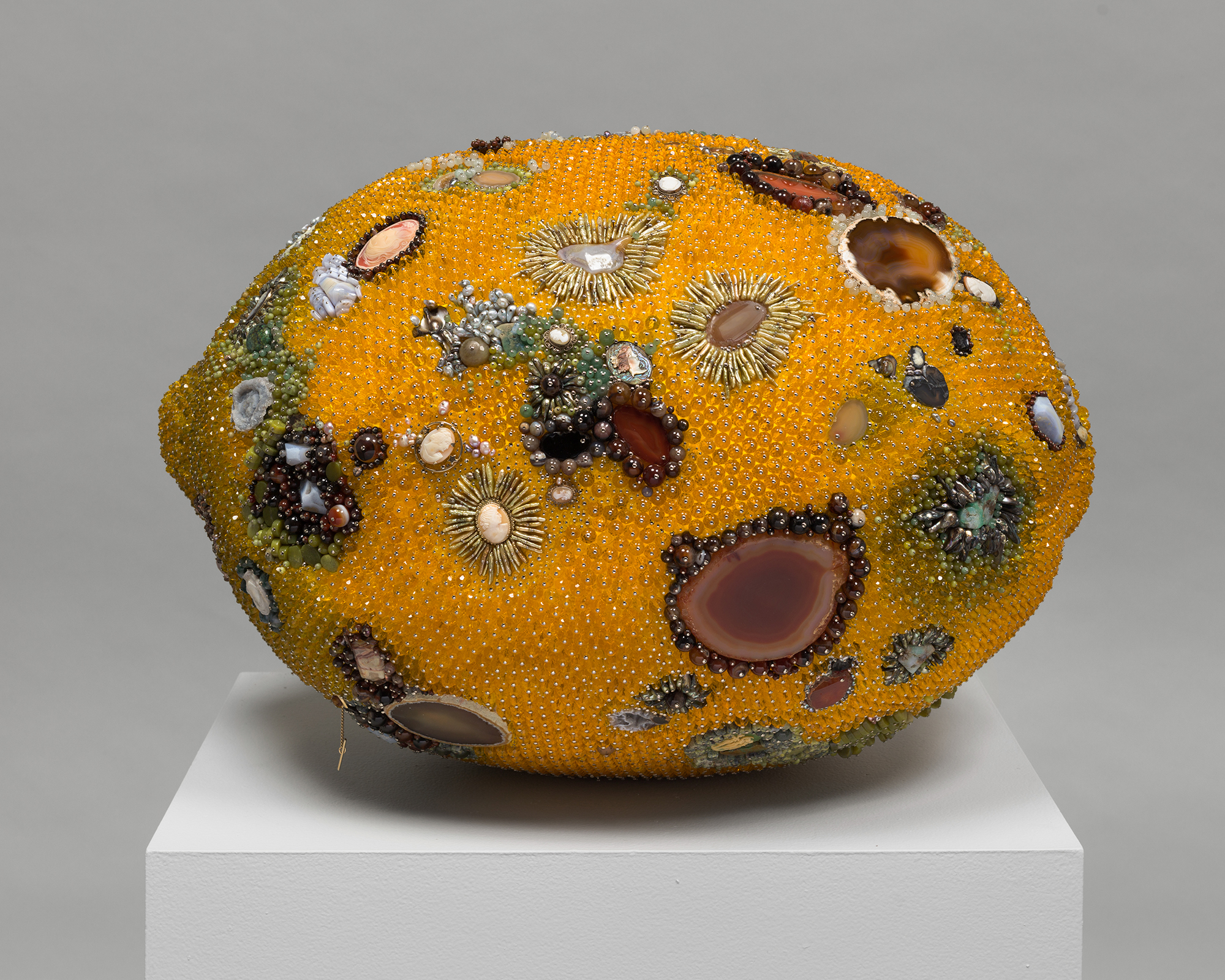 Sculpture of a lemon with molding patterns on it made of gems and rocks