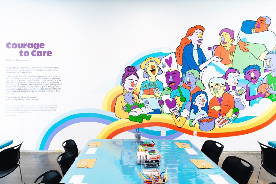 A table set up for a craft activity in front of a brightly painted mural depicting individuals demonstrating care towards each other