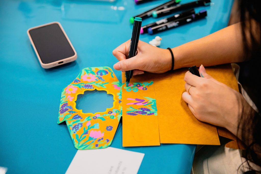 Hands decorating an unfolded box on a blue surface